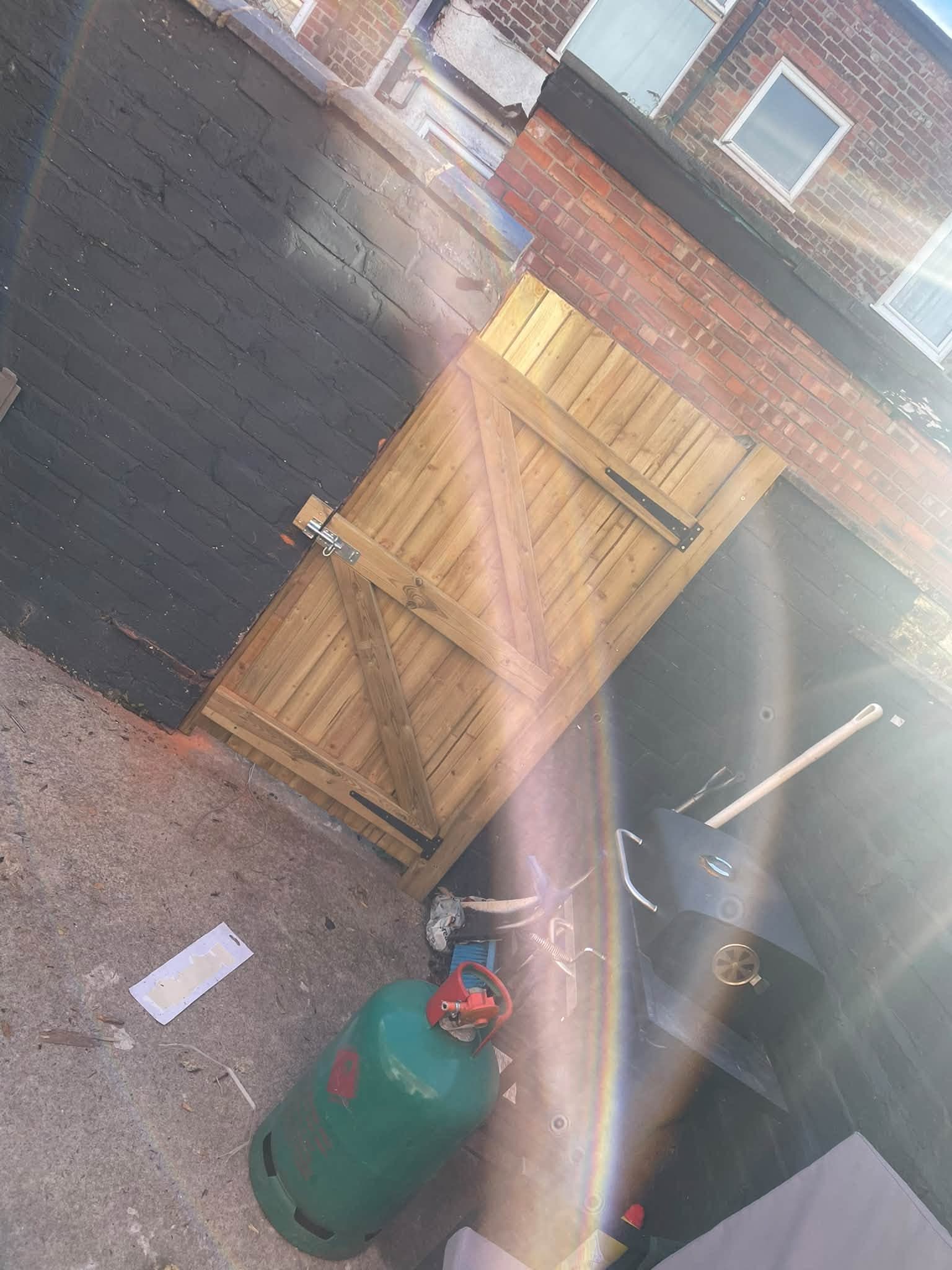 New timber garden gate fitted between dark brick garden walls